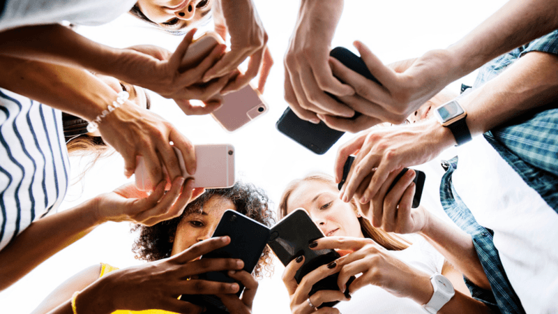 Group of people in a circle using their phones.