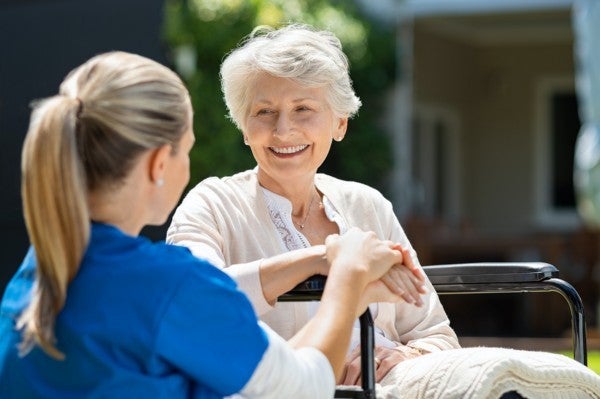 Older woman sitting outside talking to a home health aide.
