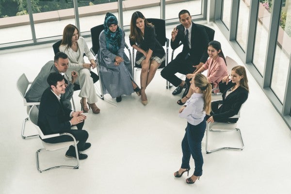 Group of colleagues sitting in a semi circle listening to a presenter.