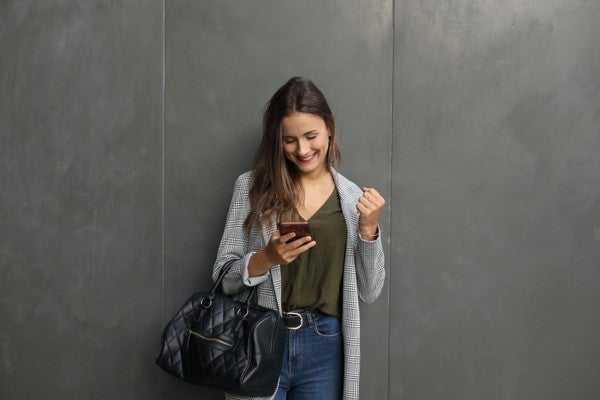 Woman leaning against the wall looking at her phone.