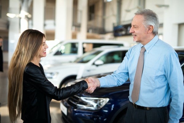 Car salesman shaking hands with a woman.