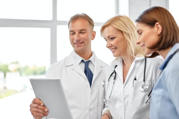 Three doctors discussing a patient chart together.