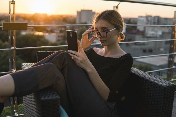 Woman sitting on a balcony looking at her phone.