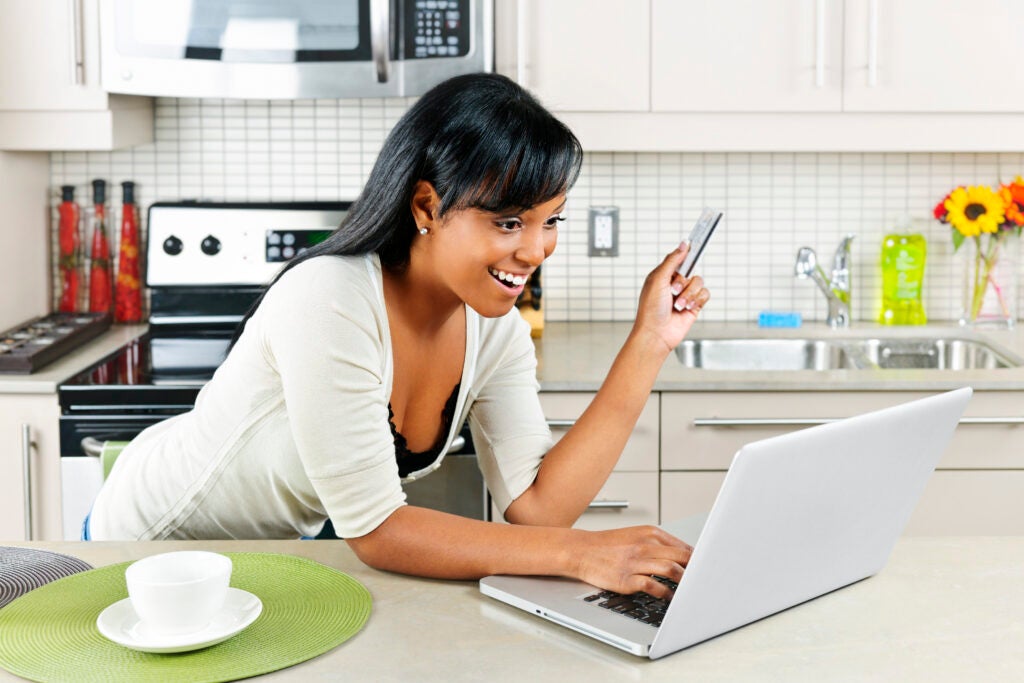 Woman online shopping in her kitchen