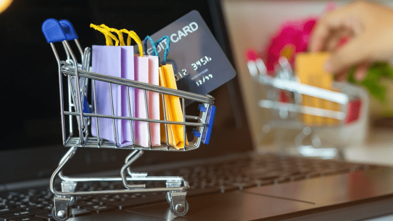 Miniature shopping cart with shopping bags and a credit card.