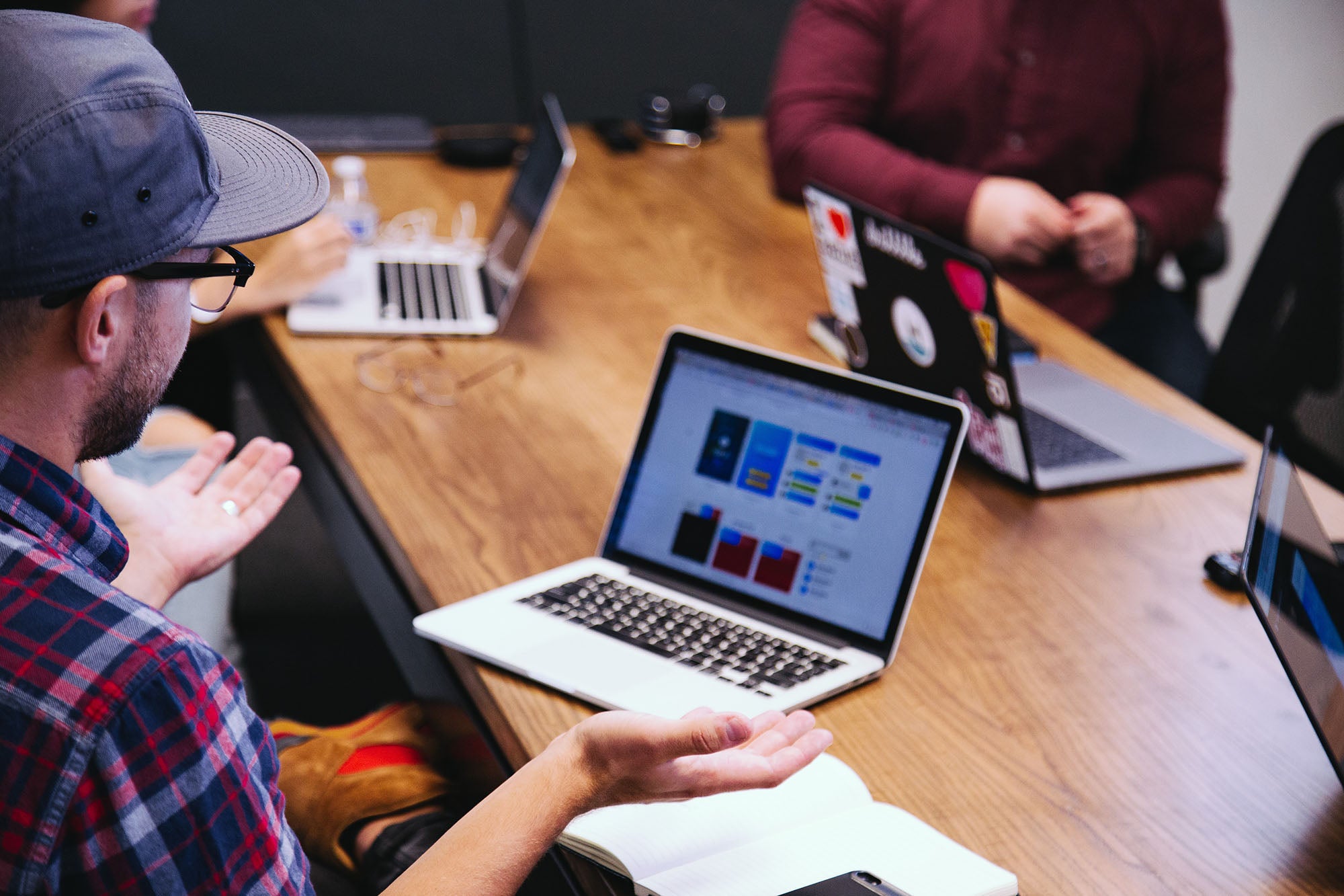 Four people at a conference table with their laptops