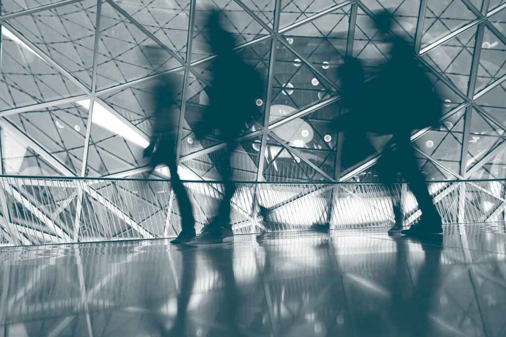 People walking through geometric glass corridor