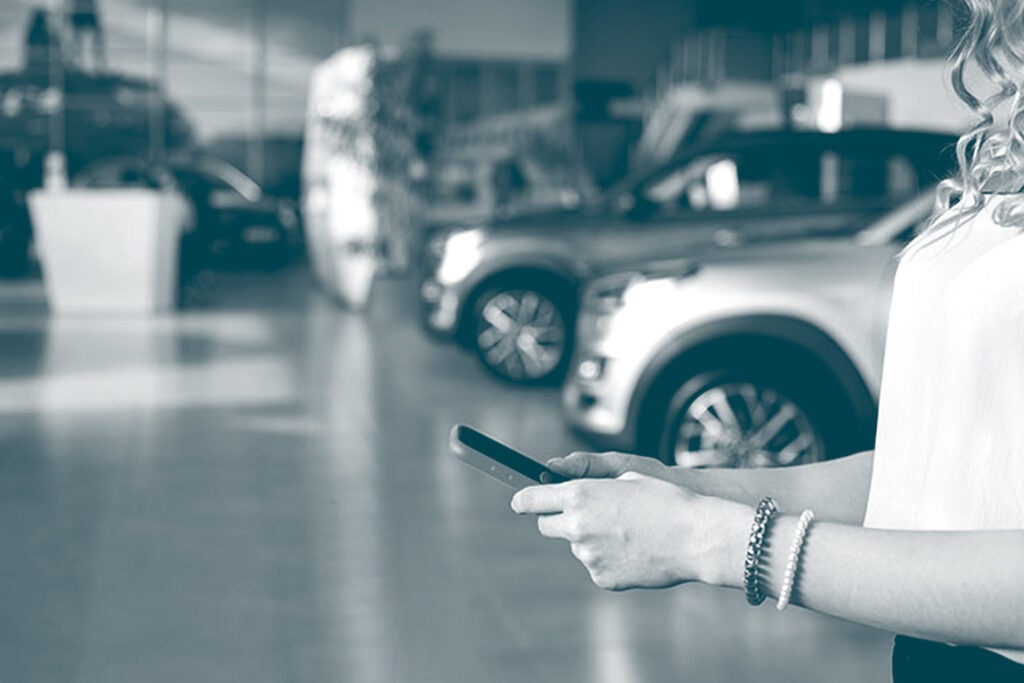 Woman holding phone in car dealership