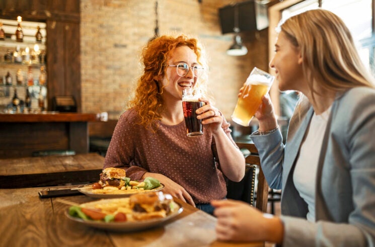 Happy Female Friends Having meal And Beer And Laughing