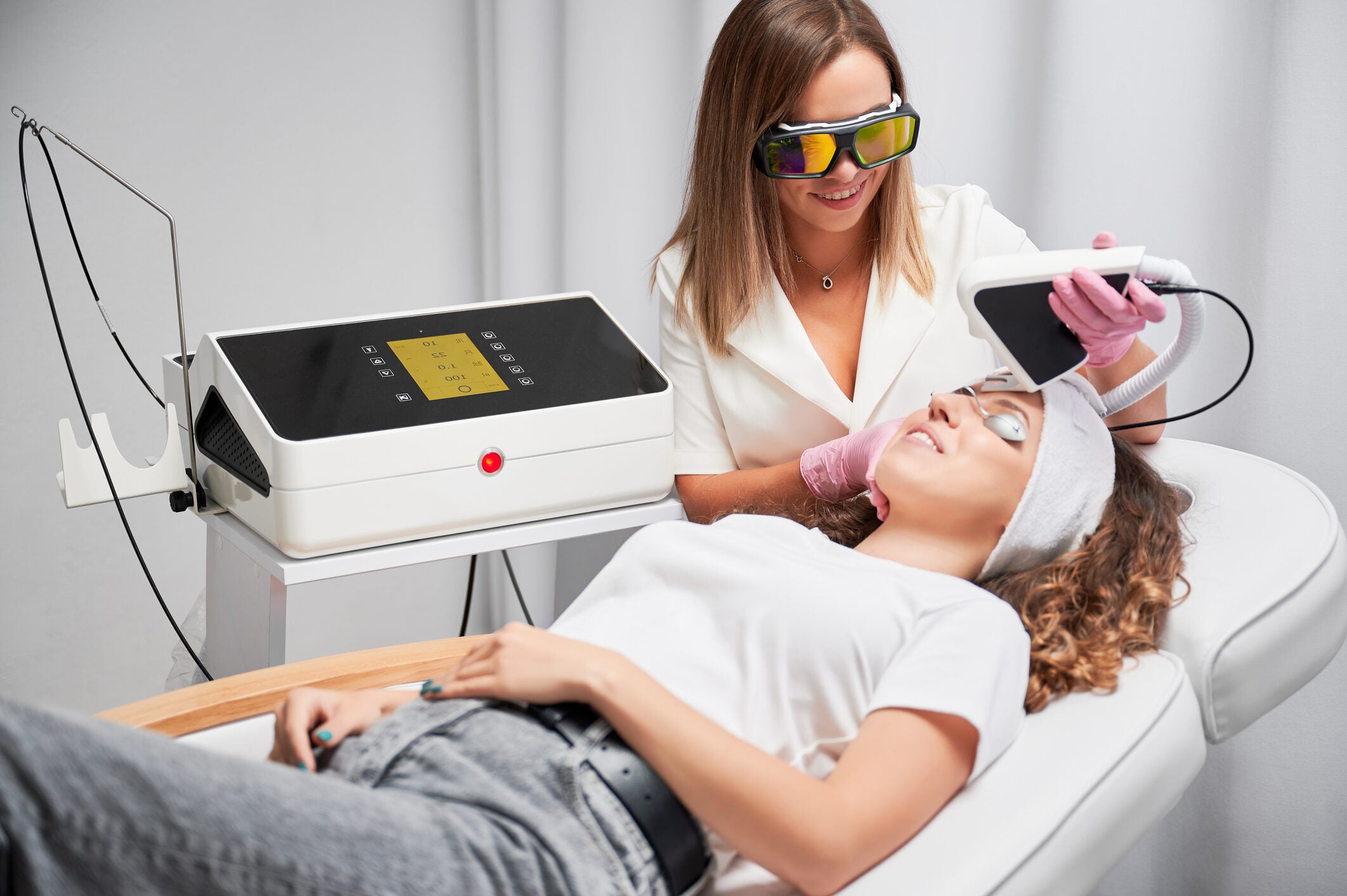 Young woman receiving laser facial treatment in cosmetology clinic.