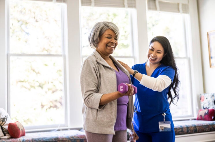 Nurse supporting woman lifting weight