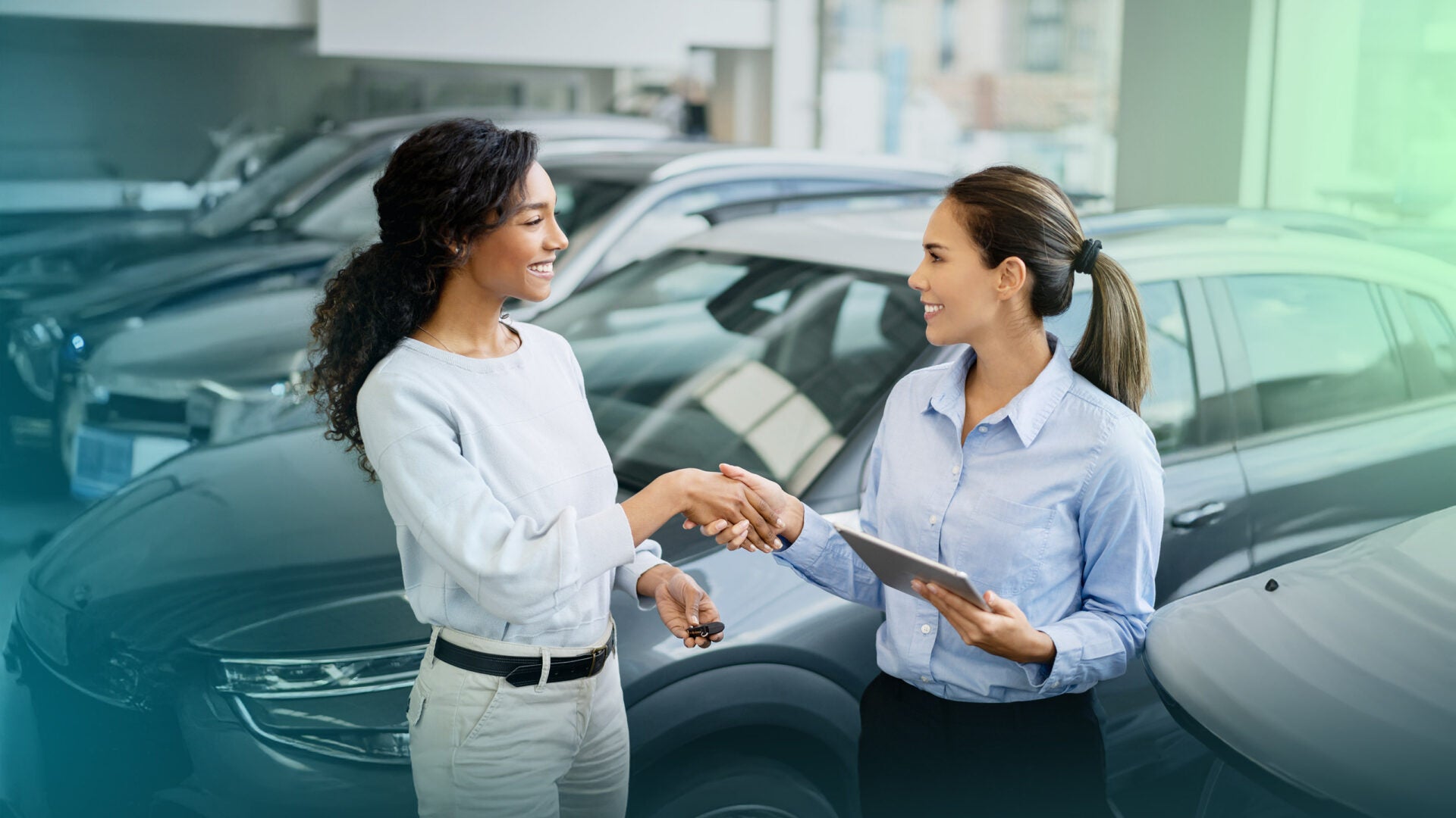 Woman auto salesman shaking hand of female customer.