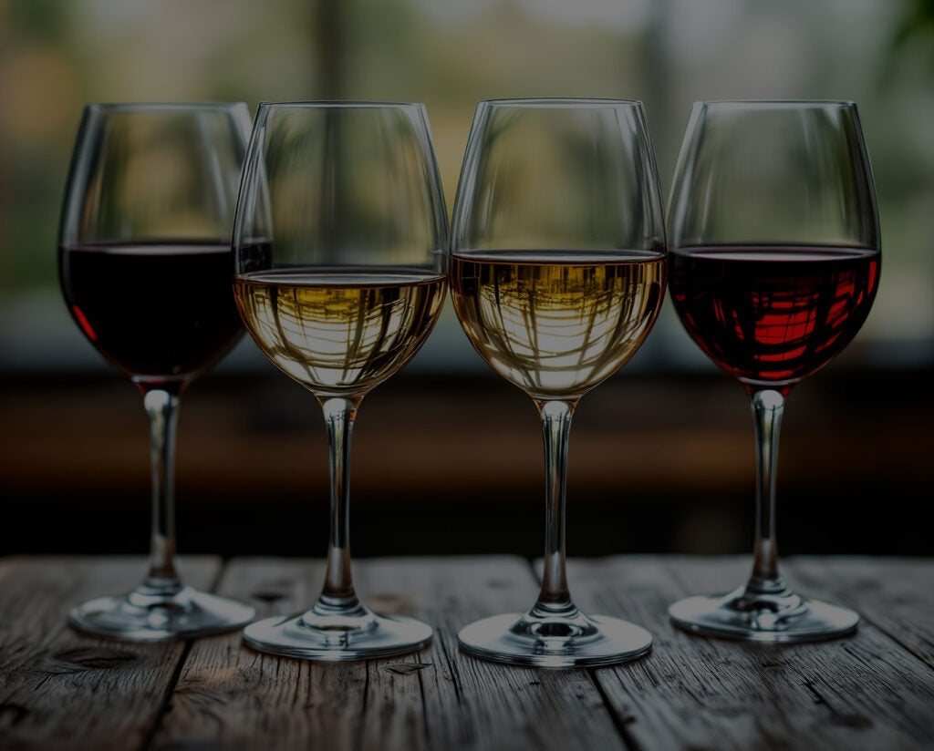 Four wine glasses filled with red and white wines.