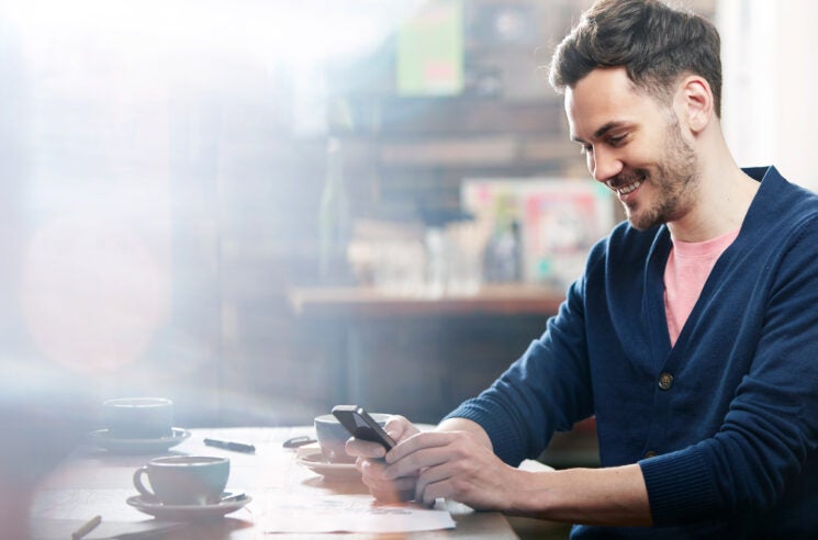 Man at desk looking a phone