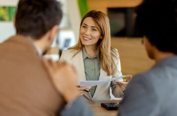 Woman at desk helping buyers with paperwork